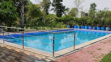 A rectangular swimming pool with a tiled edge, surrounded by a metal railing.