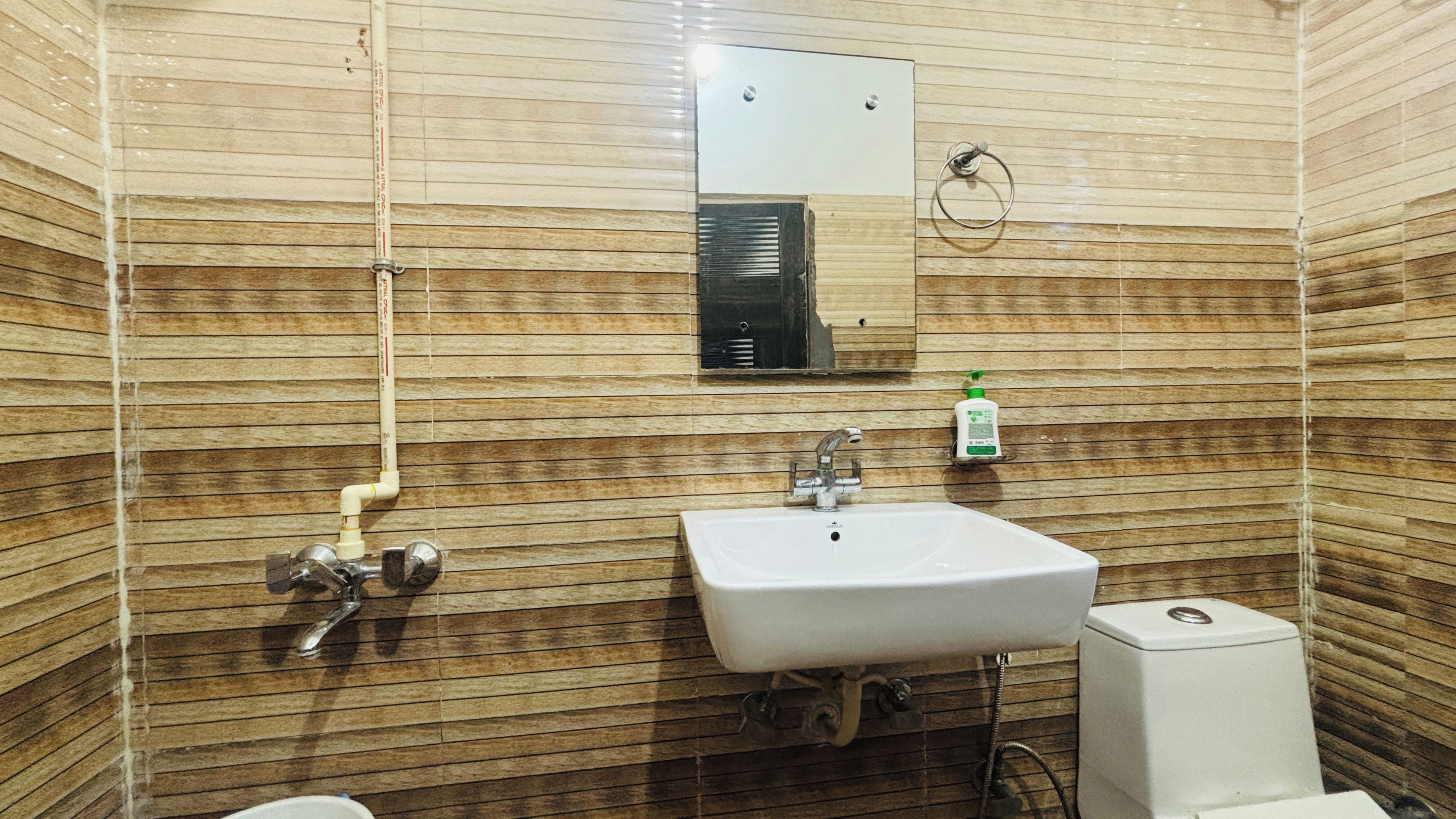 Une salle de bain équipée d'un lavabo, d'un miroir, d'un porte-serviettes et de toilettes.