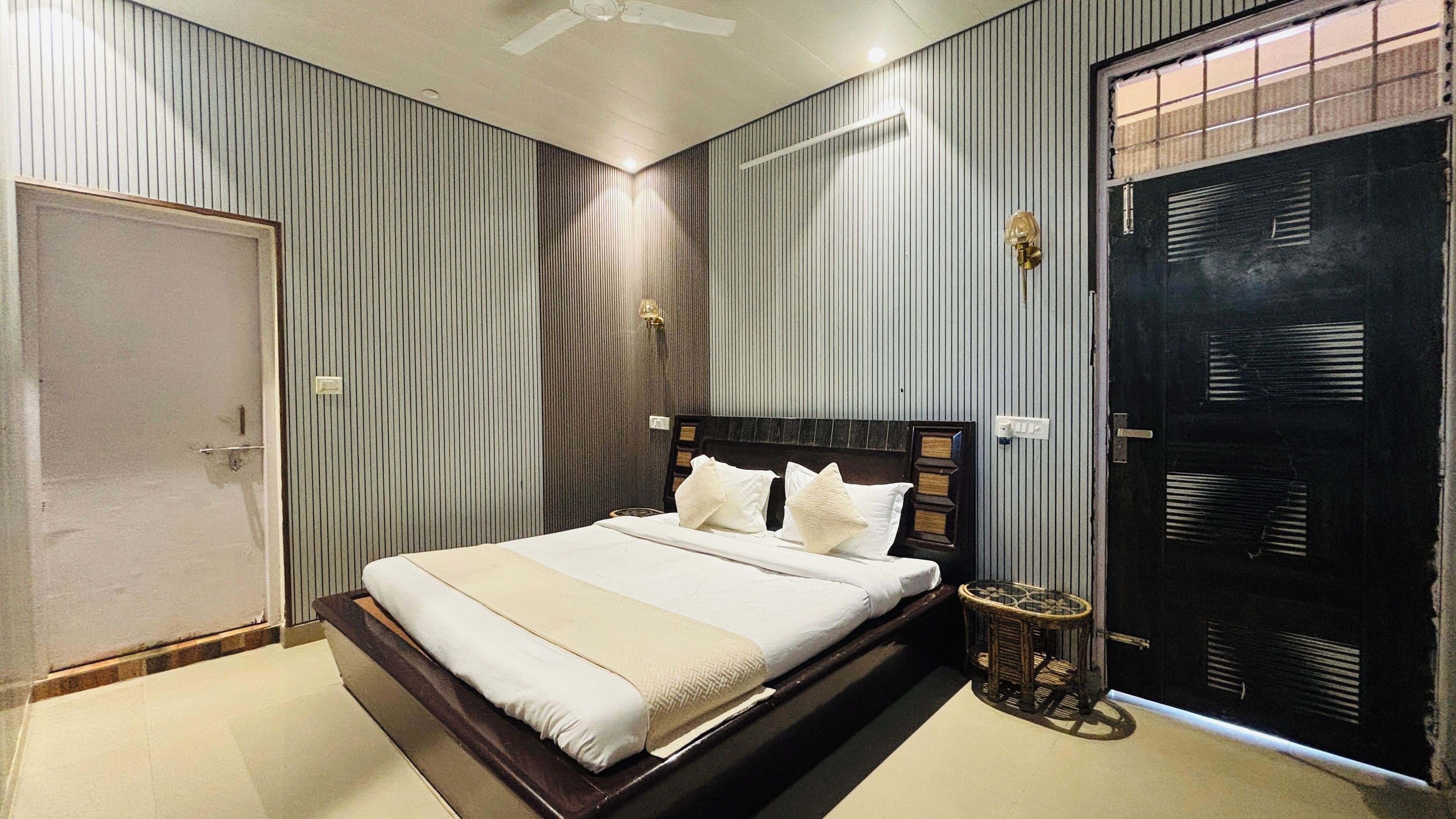A bedroom with a bed, a bedside table, a door, and a ceiling fan.