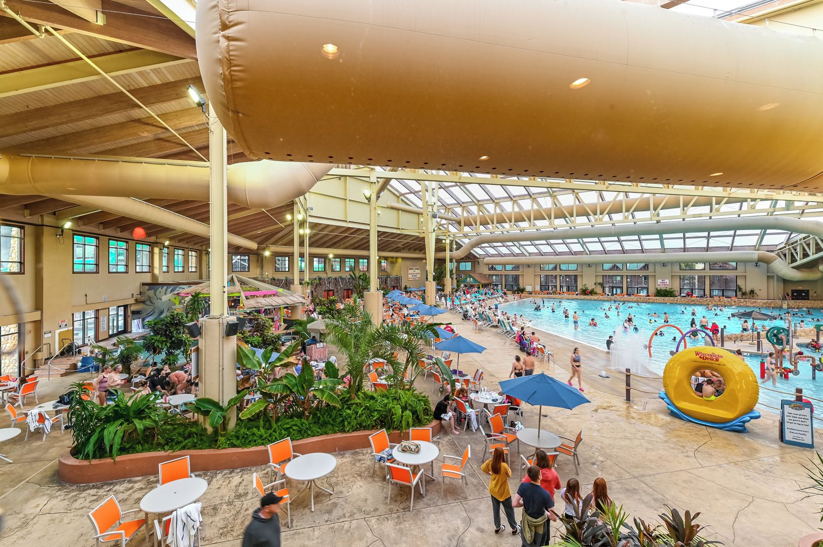 An indoor swimming pool with multiple lanes, surrounded by seating areas and covered with a large canopy.
