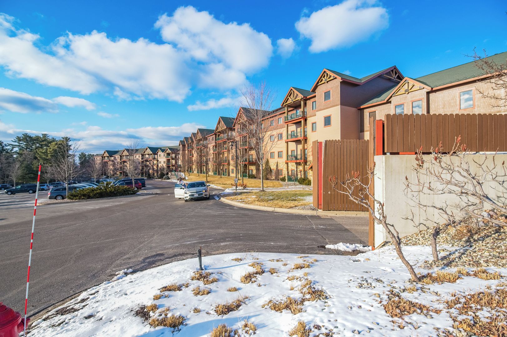 Un barrio residencial con edificios de varios pisos, una calle con coches aparcados y suelo cubierto de nieve.