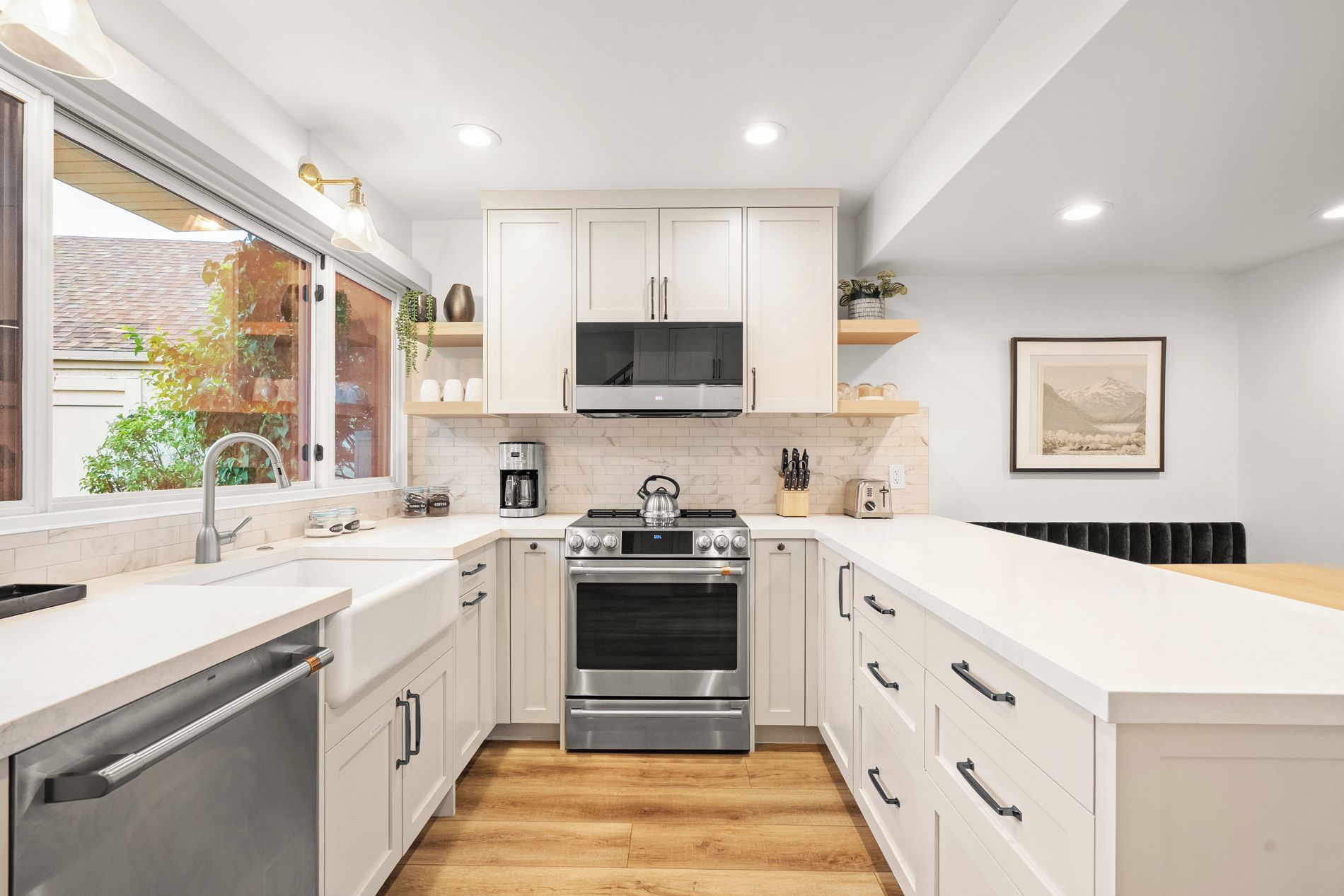 Una cocina moderna con armarios blancos, electrodomésticos de acero inoxidable y piso de madera.