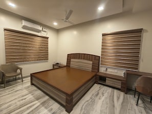 Une chambre à coucher avec un grand lit, un bureau, une chaise et un ventilateur de plafond.