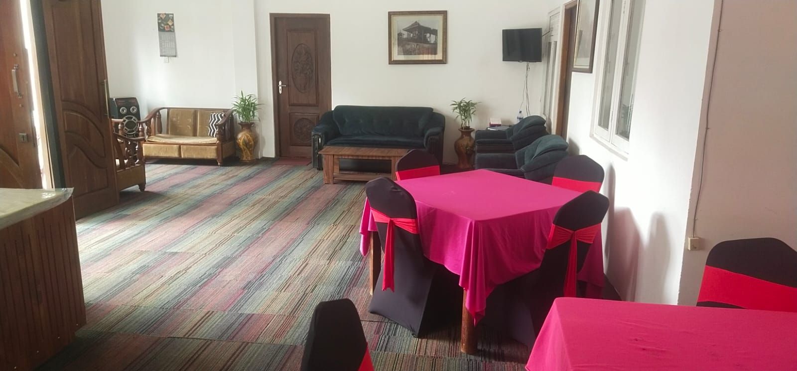 Una stanza con un tavolo da pranzo apparecchiato per quattro persone, un divano, un mobiletto in legno e una porta.