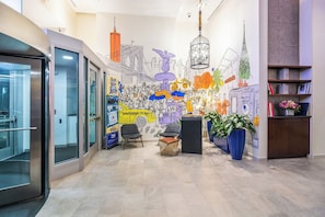 A modern lobby with a mural, seating area, and a reception desk.