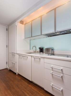 A modern kitchen with white cabinetry, a stainless steel sink, and a toaster.