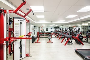 A gym with red and black exercise equipment, a mirrored wall, and a variety of weight machines.