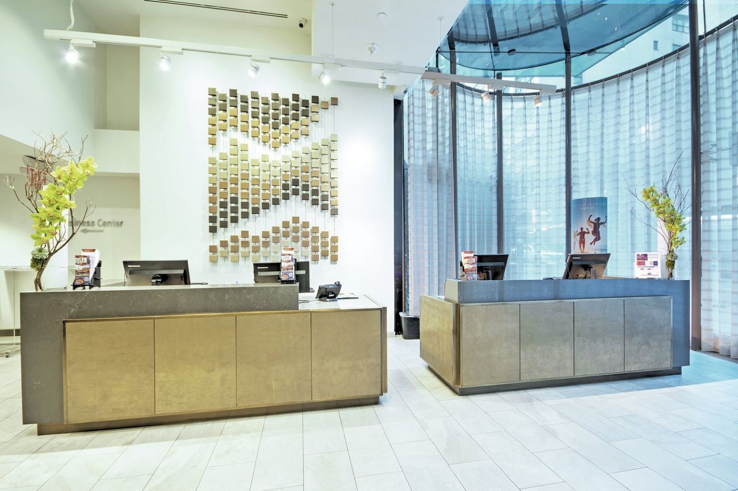 A modern reception area with two counters, a wall-mounted display of various items, and a large glass window.