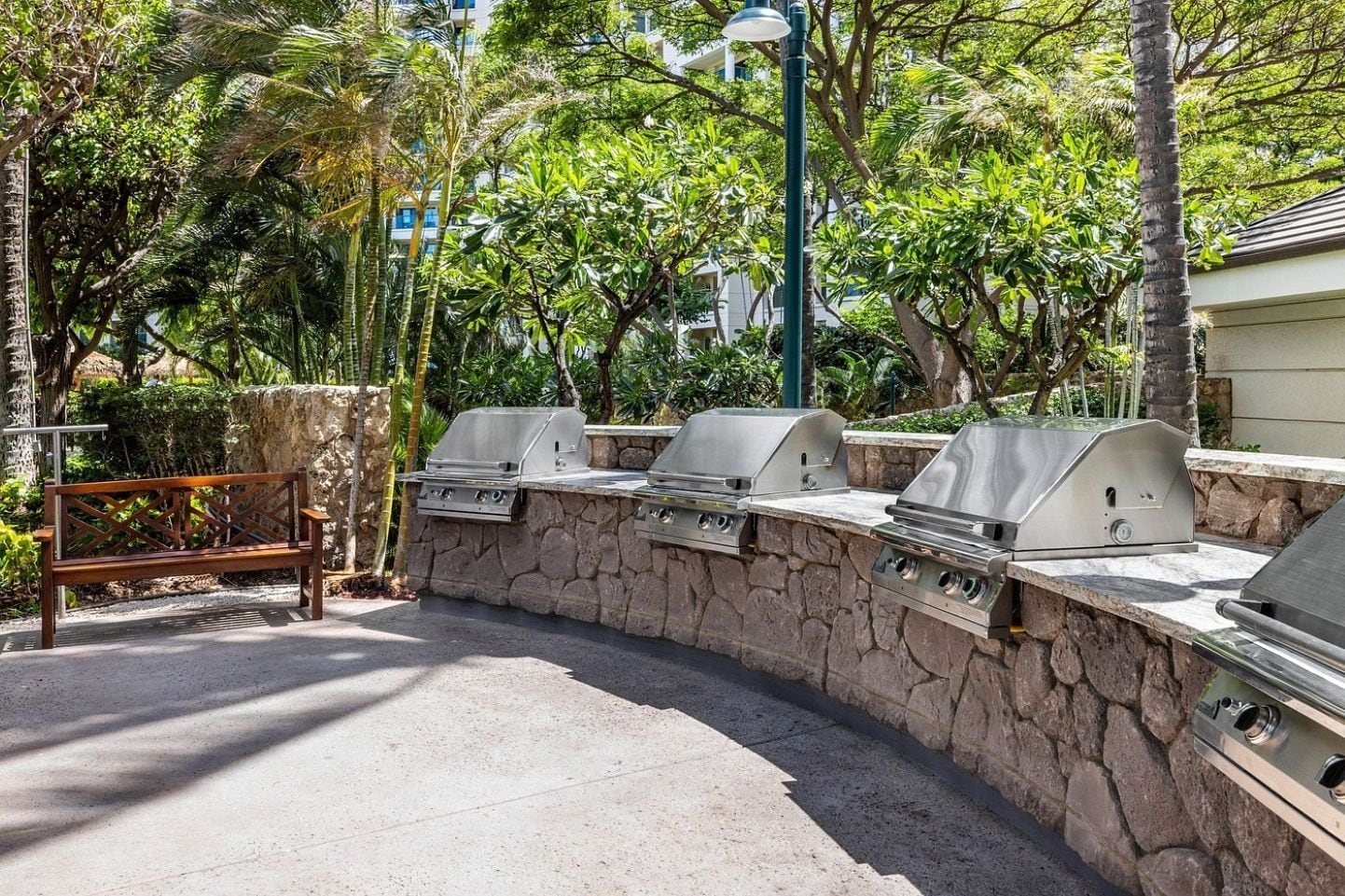 An outdoor barbecue area with stone walls and three grills.