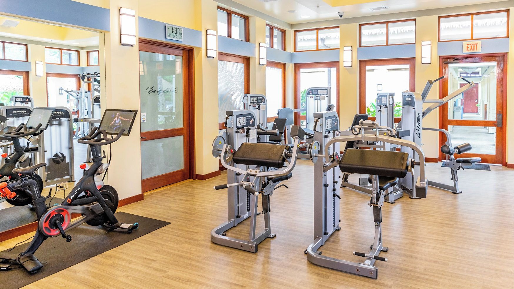 Un gimnasio con máquinas de cardio, estaciones de pesas y espejos.