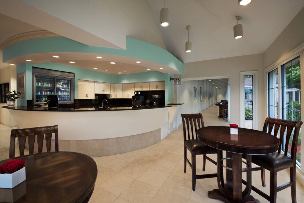 Una cocina moderna con una isla curva, un comedor con mesa redonda y vistas al exterior a través de grandes ventanales.