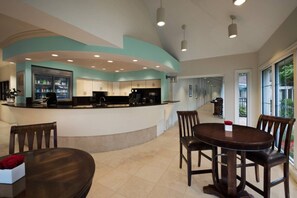 Una cocina moderna con una isla curva, un comedor con mesa redonda y vistas al exterior a través de grandes ventanales.