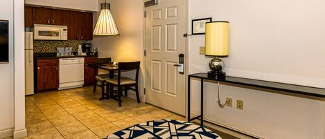 A compact kitchen with a microwave, coffee maker, and dining table with chairs.