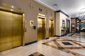 A hotel lobby with a marble floor, gold elevators, and a reception desk. - New Orleans | Streetcar Ride | Pool & Hot Tub (New Orleans)