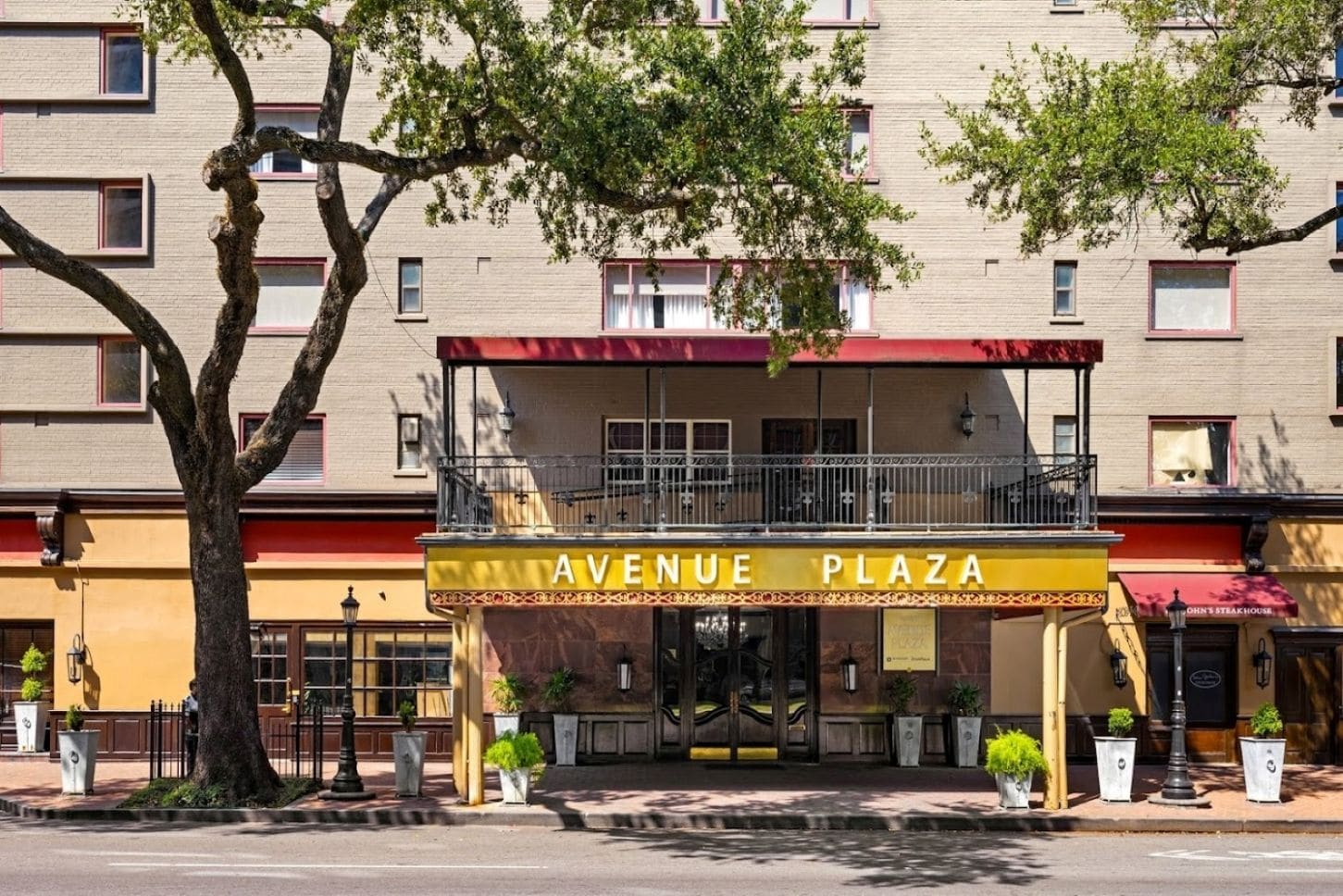A building with a sign reading 'AVENUE PLAZA' and a balcony with railings.