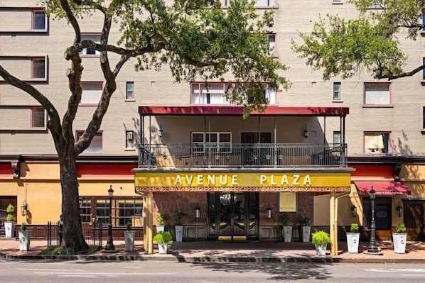 Um edifício com uma placa indicando 'AVENUE PLAZA' e uma varanda com grades.