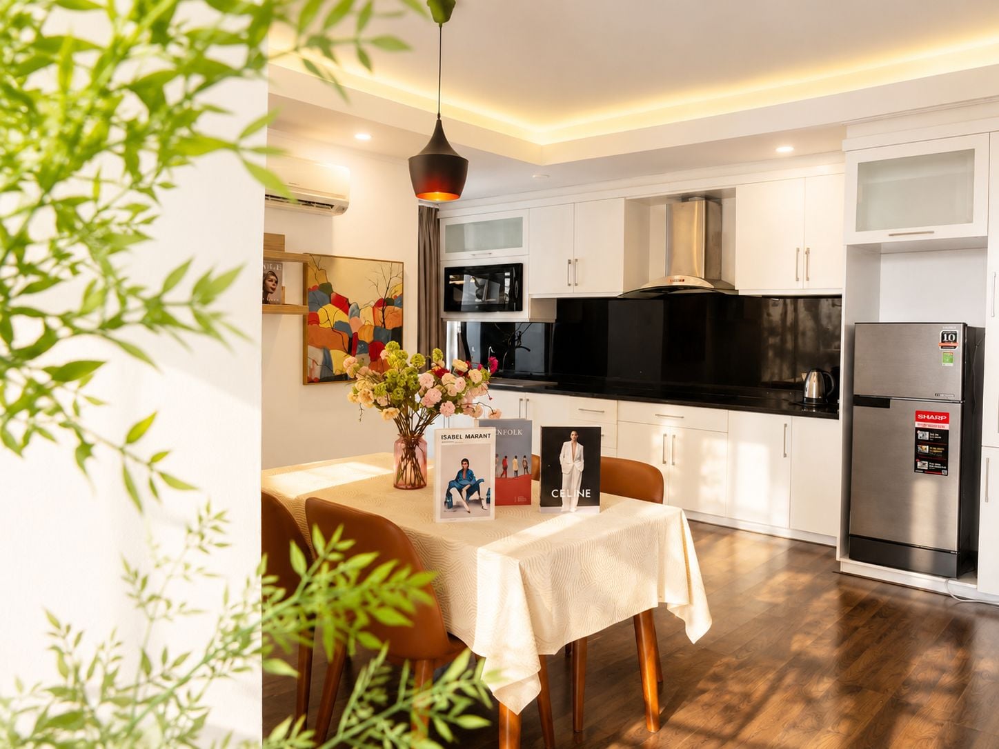 A modern kitchen with white cabinetry, a black countertop, and a stainless steel refrigerator.