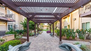 A covered outdoor area with a brick pathway, potted plants, and a dolphin sculpture. - Anaheim | Disneyland Weekend Stay | Pool & Hot Tub (Anaheim)