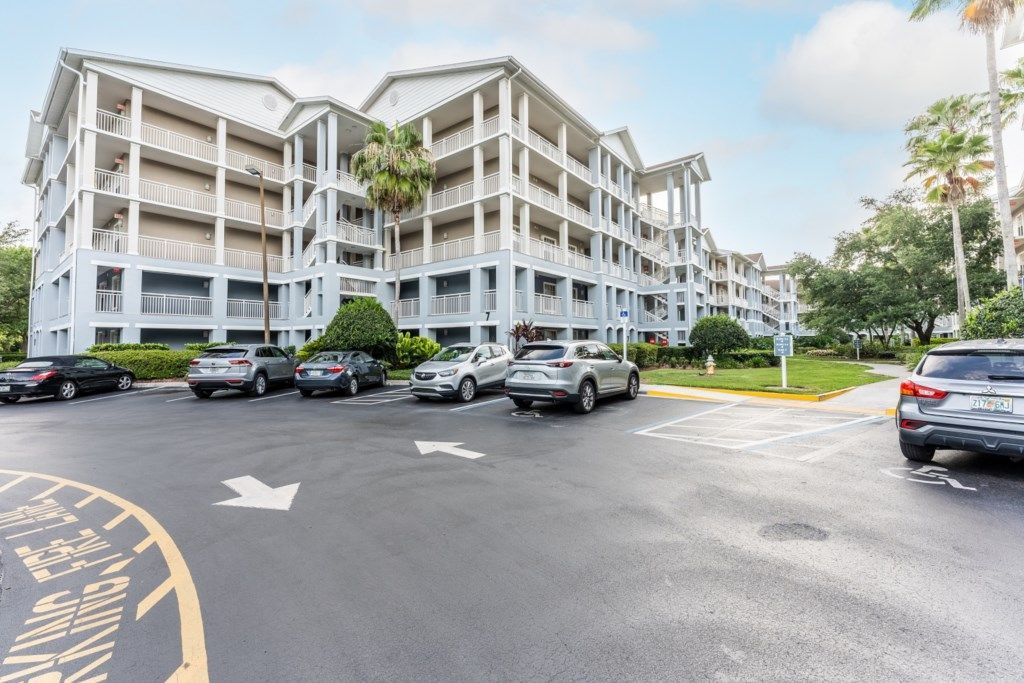 Een meerhoog hotel met een parkeerplaats, aangegeven parkeerplaatsen en een heldere lucht.