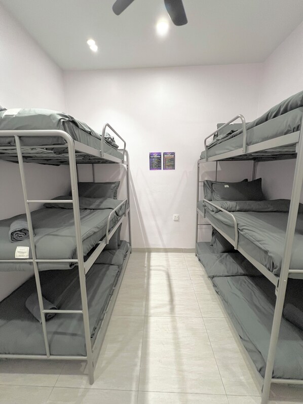 A room with bunk beds, a ceiling fan, and two informational posters on the wall.
