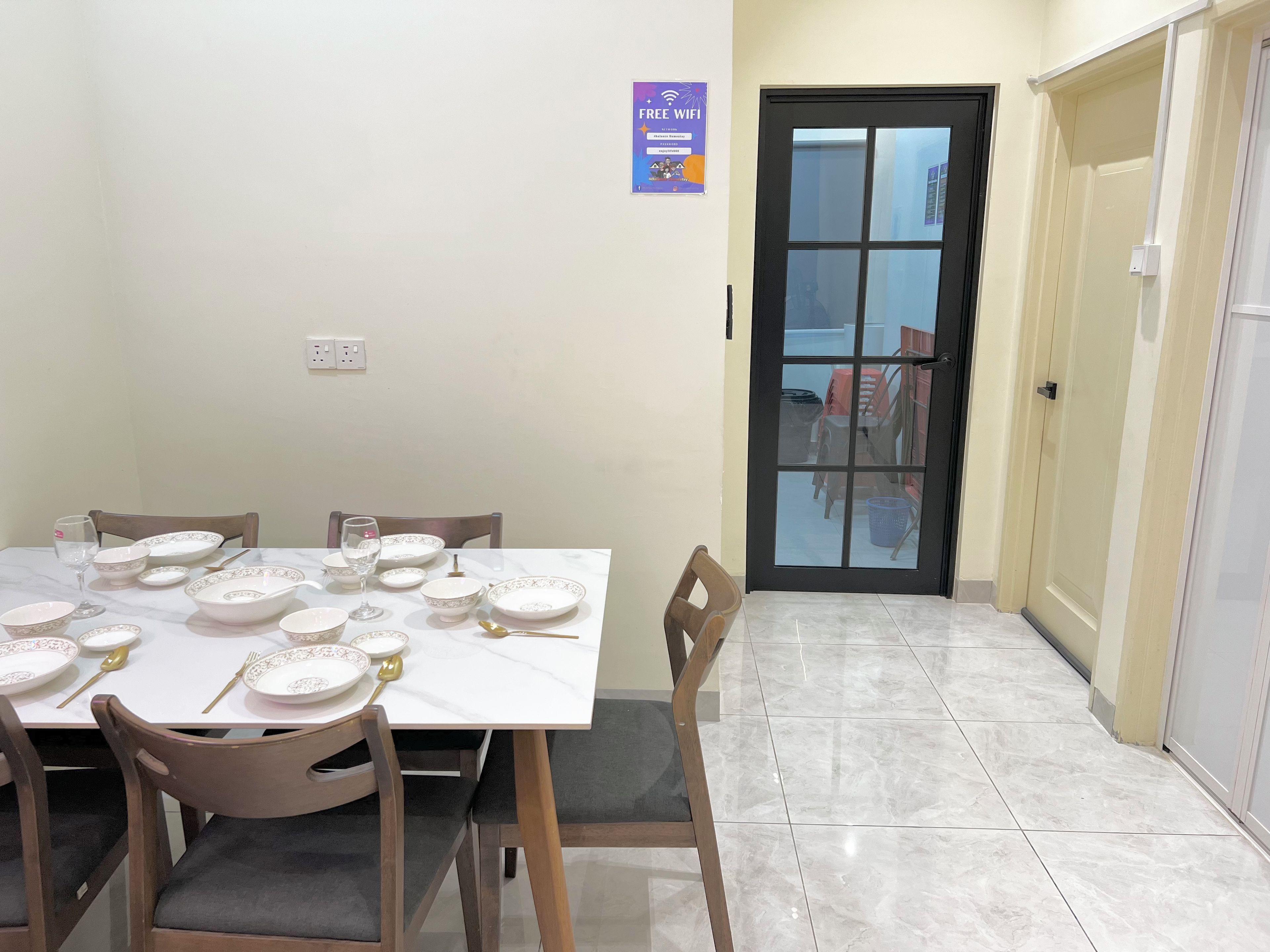 A dining area with a table set for four, chairs, and a door leading to a balcony.