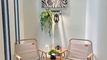 Una habitación con dos sillas, una obra de arte con motivos de cebra, una planta colgante y un farol en un estante.