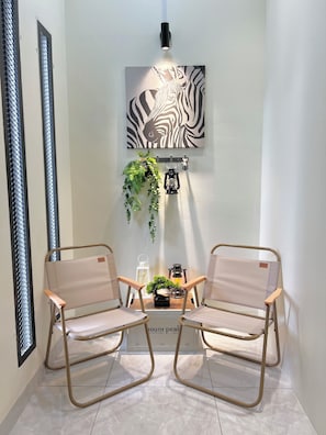 A room with two chairs, a zebra artwork, a hanging plant, and a lantern on a shelf.