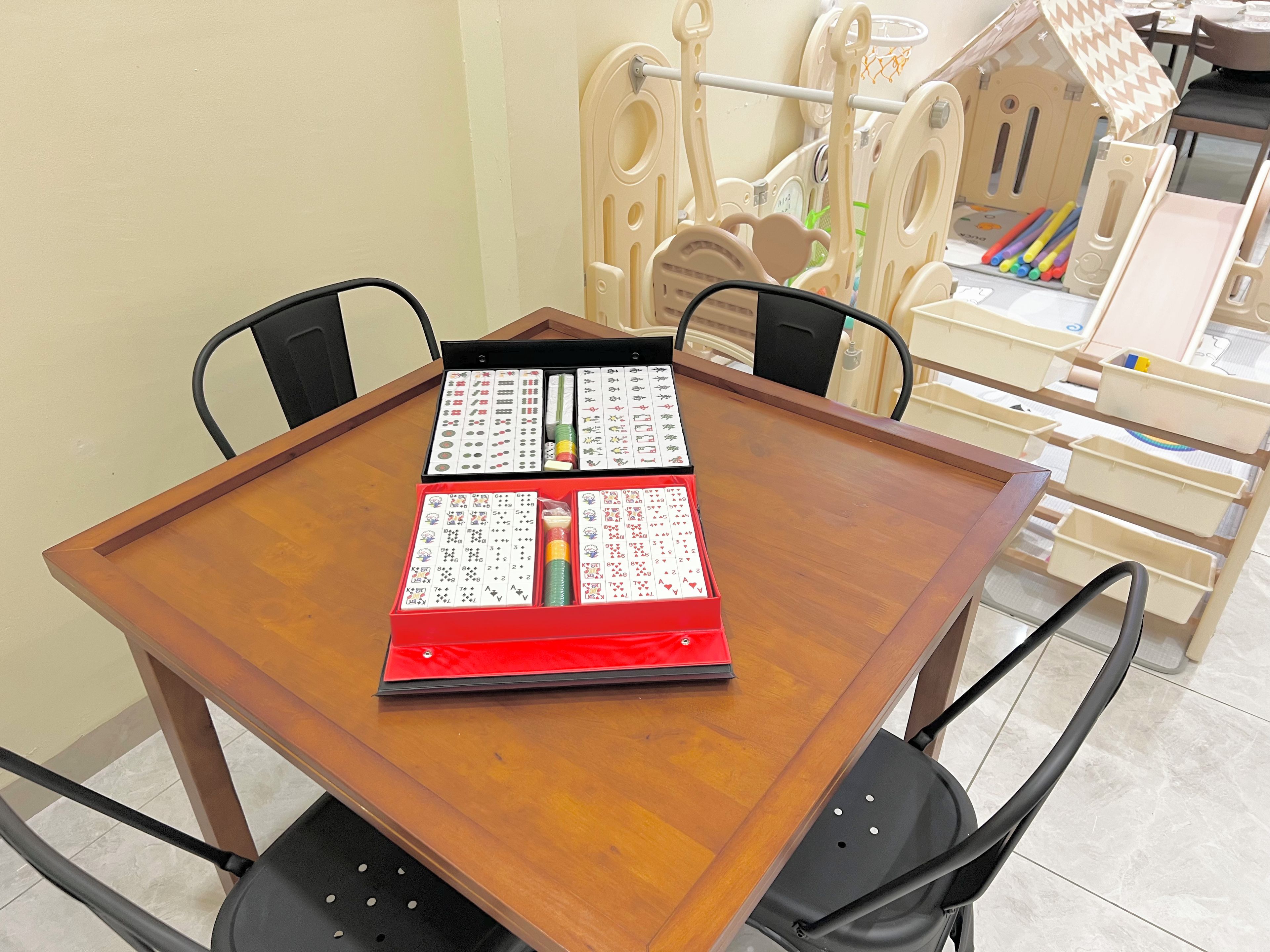 Een houten eettafel met een rode map en speelkaarten.