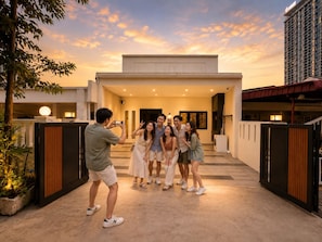 A group of people posing in front of a modern building with a flat roof and large windows.