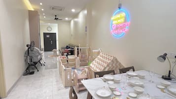 A dining area with a table set for four, chairs, a ceiling fan, and a neon sign on the wall.