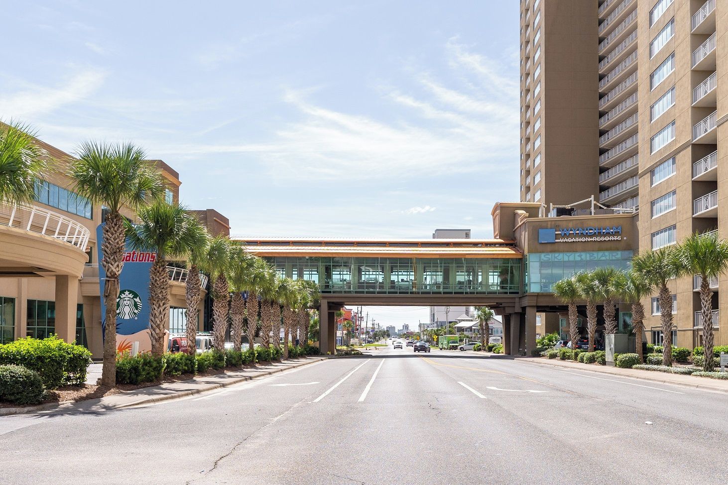 A street with a pedestrian bridge, a building with a sign for Waynham Vacation Resorts, and a Starbucks logo.