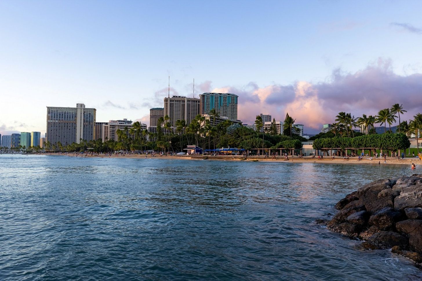 A coastal cityscape with high-rise buildings, a beach, and palm trees.