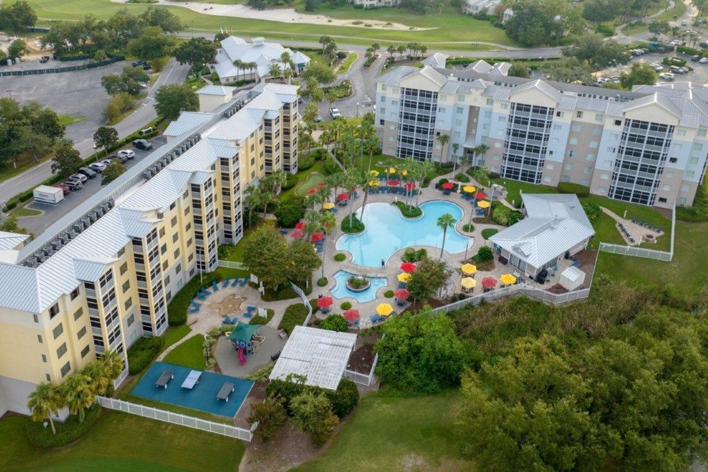 A hotel with multiple buildings, a swimming pool, and a landscaped area with umbrellas.