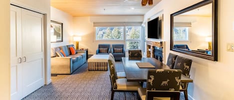 A modern interior with a dining area, sofa, and a television mounted on the wall.