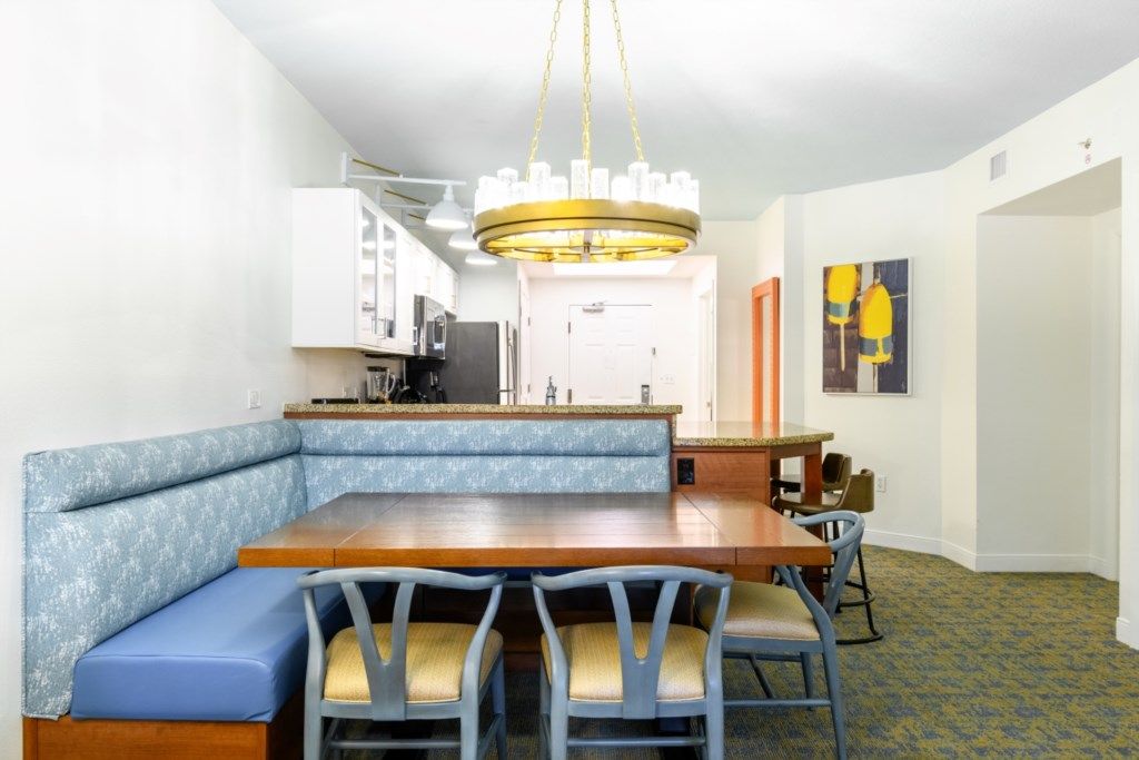 Un espace repas avec une table en bois et des bancs rembourrés de coussins bleus.