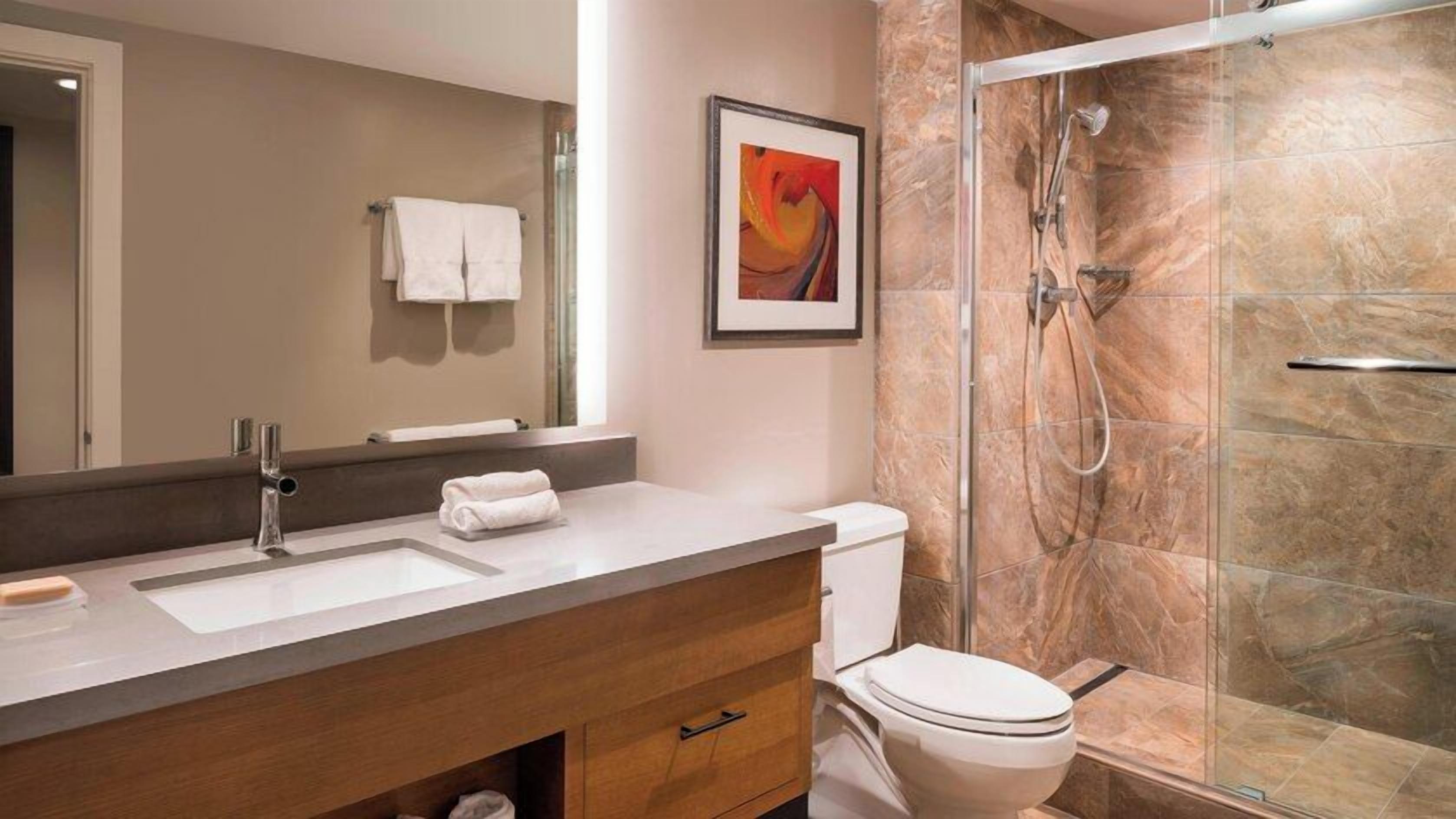 A modern bathroom with a sink, toilet, and shower.