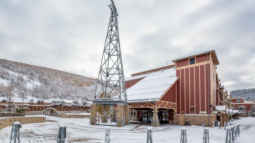 Un edificio innevato con un'alta torre, un ingresso coperto e montagne sullo sfondo.