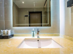 Un baño moderno con un espejo grande, un lavamanos y artículos de aseo.