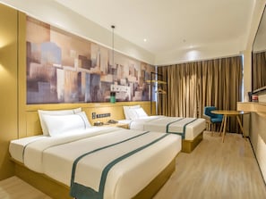 Habitación de hotel con dos camas, un escritorio, una silla y un cuadro abstracto grande en la pared.