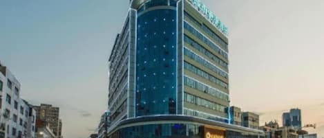 Un hotel de varios pisos con fachada curva, ventanas amplias y señalización llamativa.