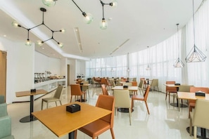 Un amplio comedor con varias mesas y sillas, un mostrador de buffet e iluminación colgante.