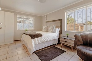 Een slaapkamer met een bed, nachtkastje en een raam.