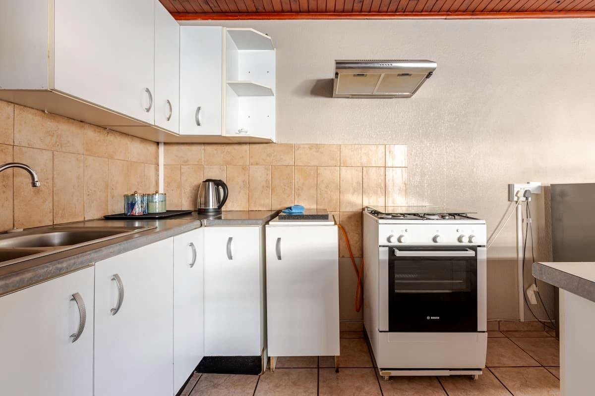 Een compacte keuken met witte kastjes, een gasfornuis van Bosch en een inbouwoven.