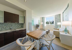 A modern kitchen with dark cabinets, a tiled backsplash, and a wooden dining table with wicker chairs.