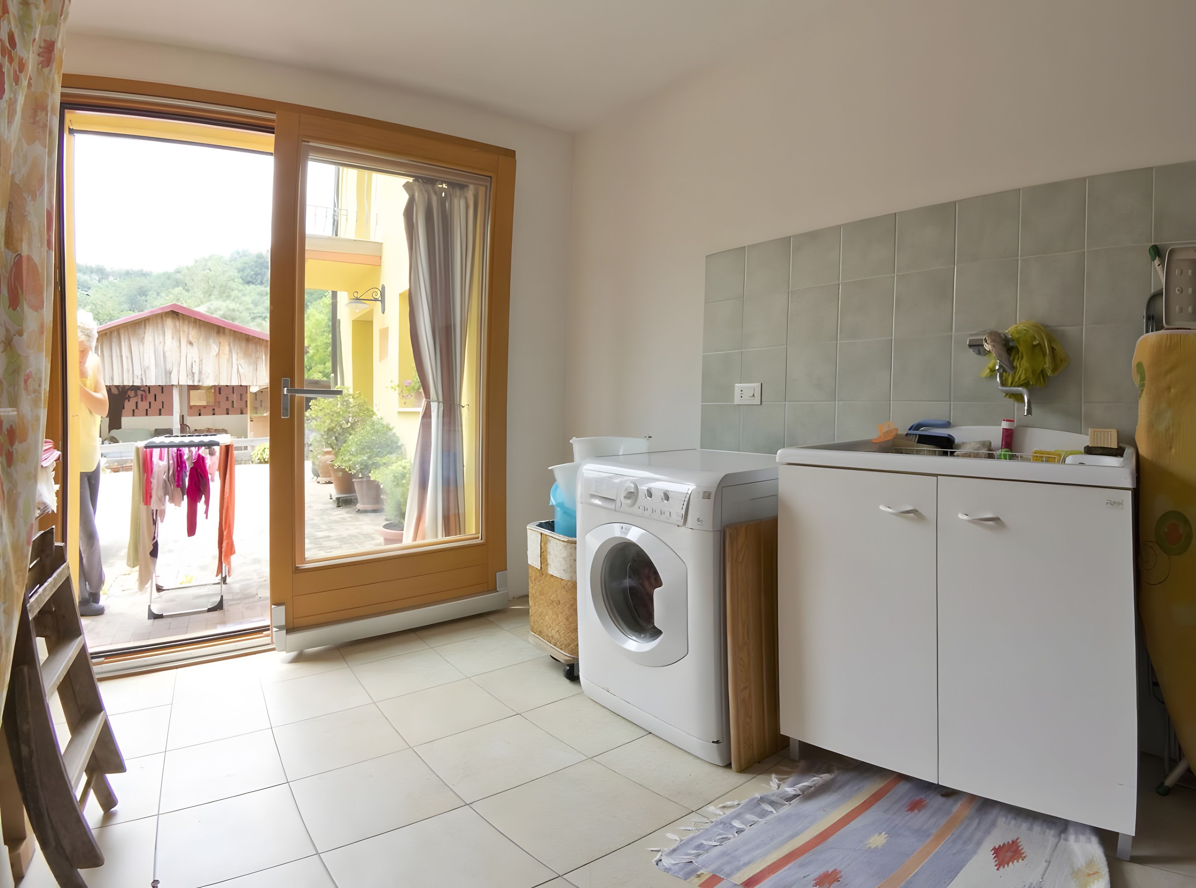 Une buanderie équipée d’un lave-linge, d’un étendoir et d’un évier avec un miroir.
