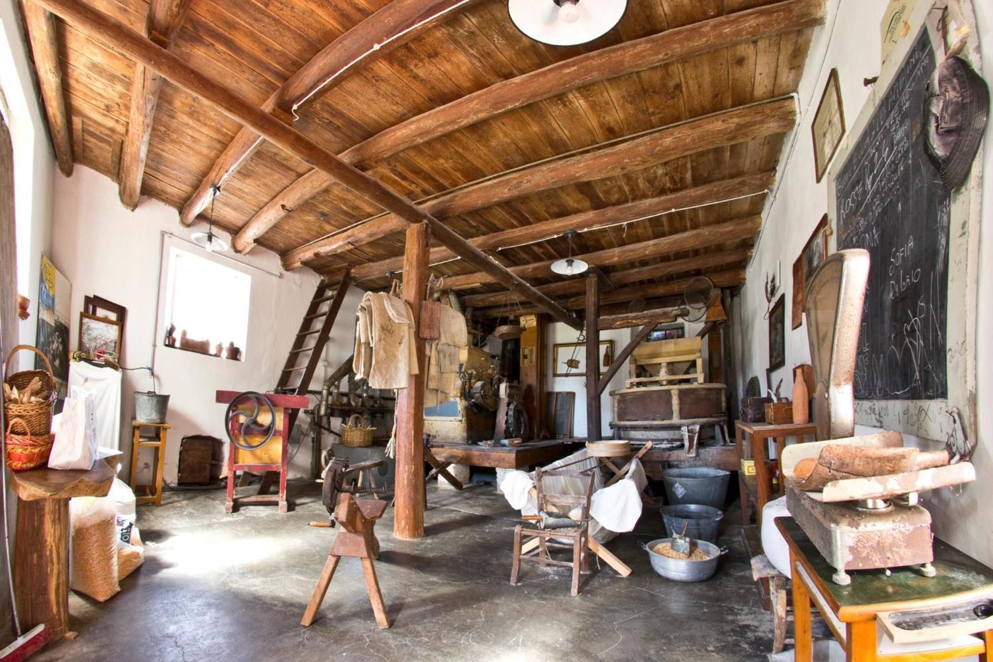 Un intérieur caractérisé par un haut plafond en bois, des meubles rustiques et divers outils et équipements.