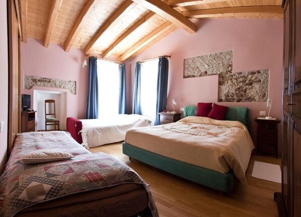 Un dormitorio con dos camas, techo de madera y pared de piedra.