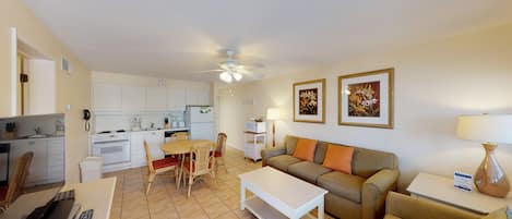 A compact living space with a kitchenette, a dining area, and a seating area with a sofa and chairs.