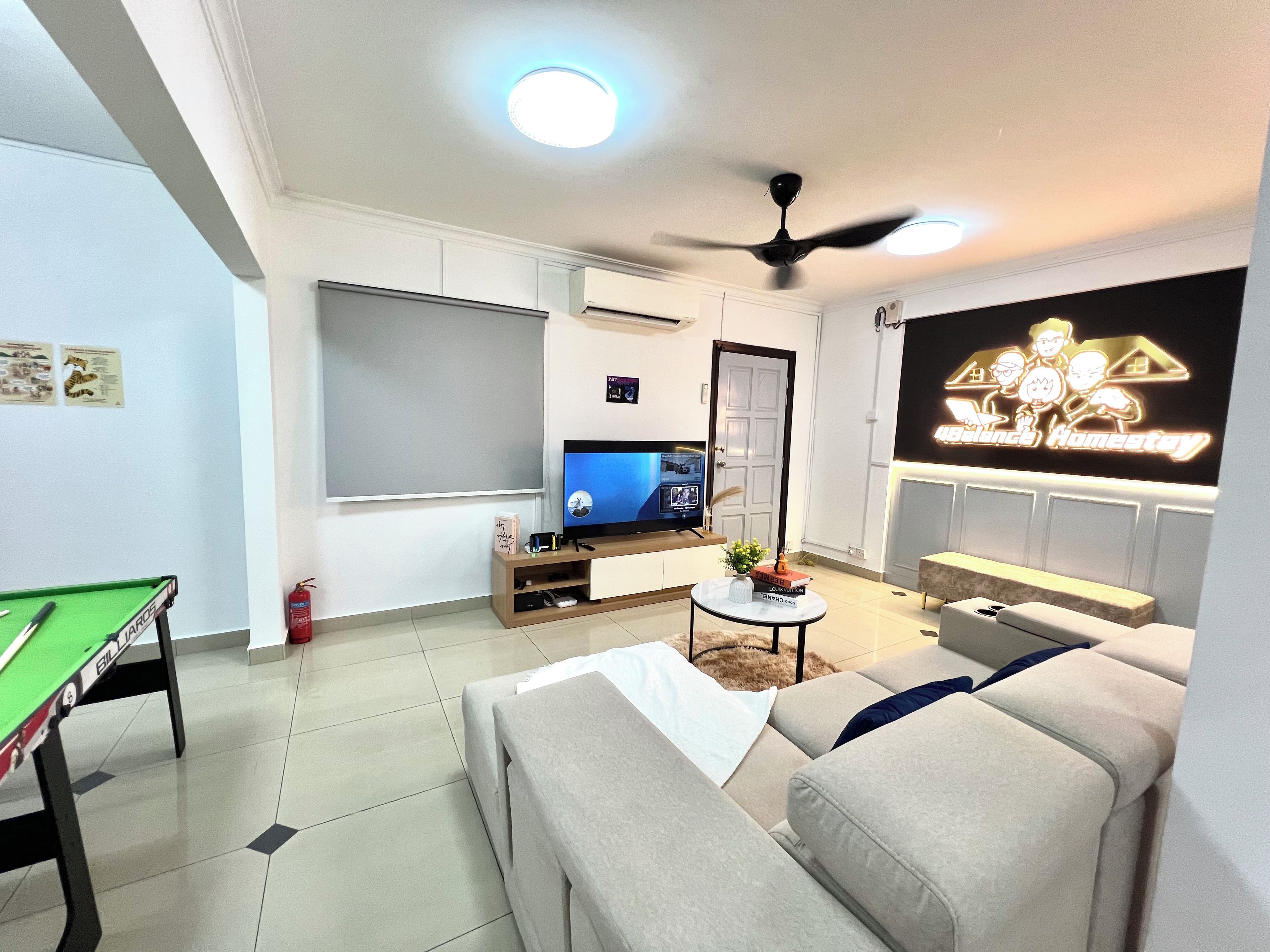A living room with a pool table, a sofa, a TV, and a ceiling fan.