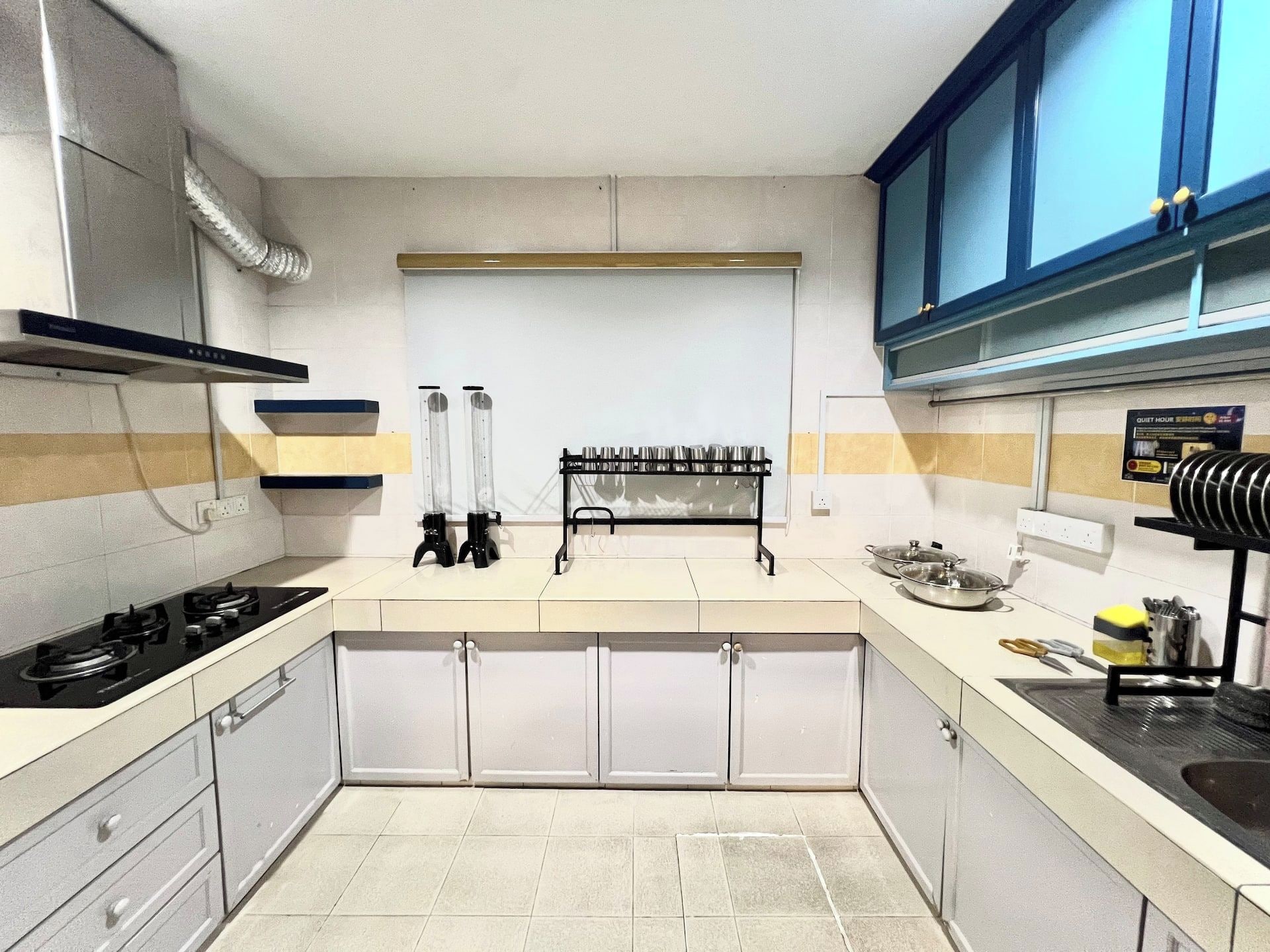 A compact kitchen with a gas stove, a built-in oven, and a sink. There are cabinets and a countertop with a hanging rack.